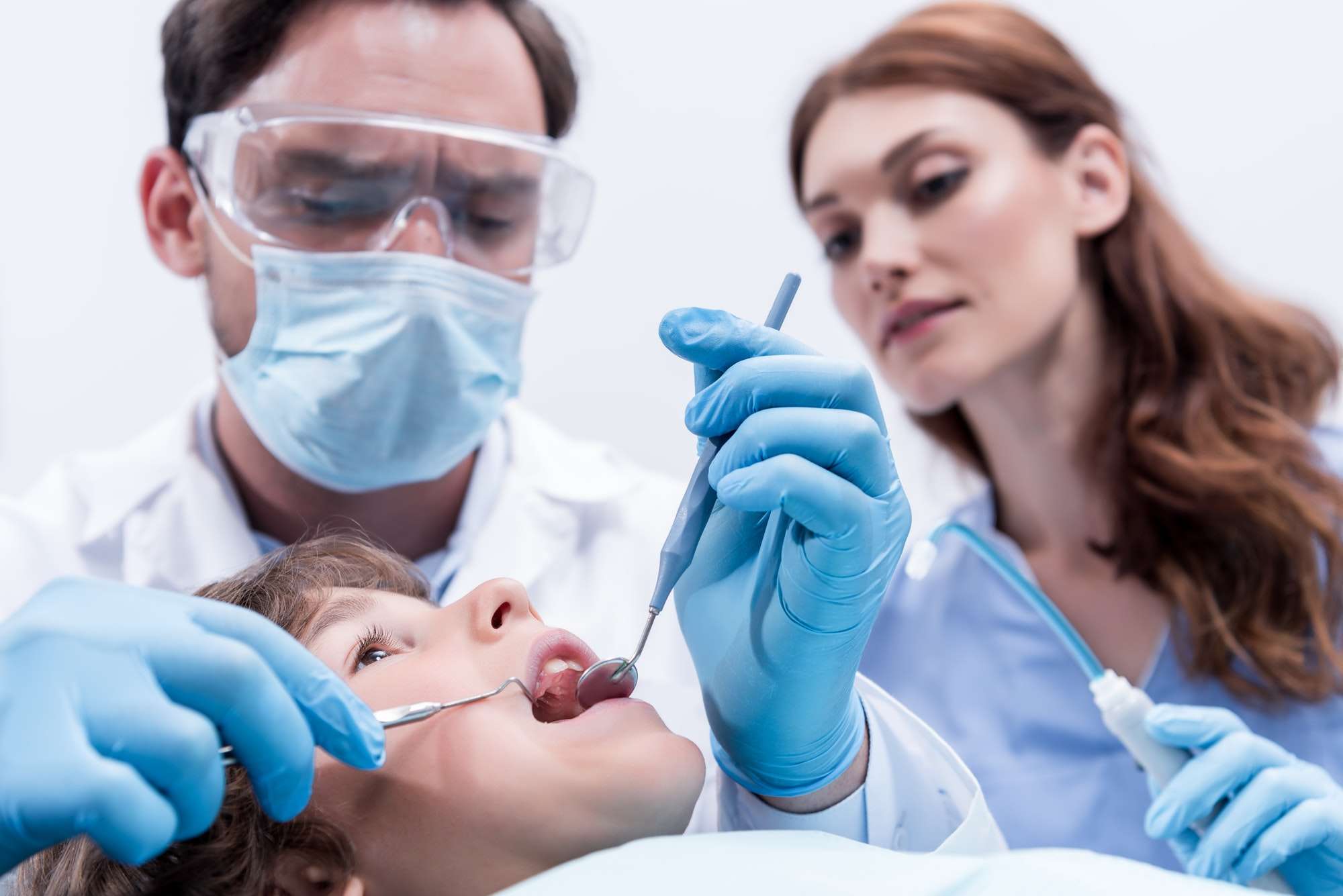 low-angle-view-of-dentists-examining-teeth-of-little-boy-at-dentist-office.jpg